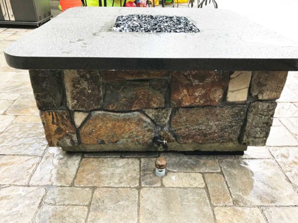 beautiful stone fire table with pavers on outside edge