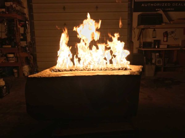 large fabricated stone fire pit with fire rock, propane powered.
