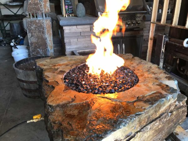 large fabricated stone fire pit with fire rock, propane powered.