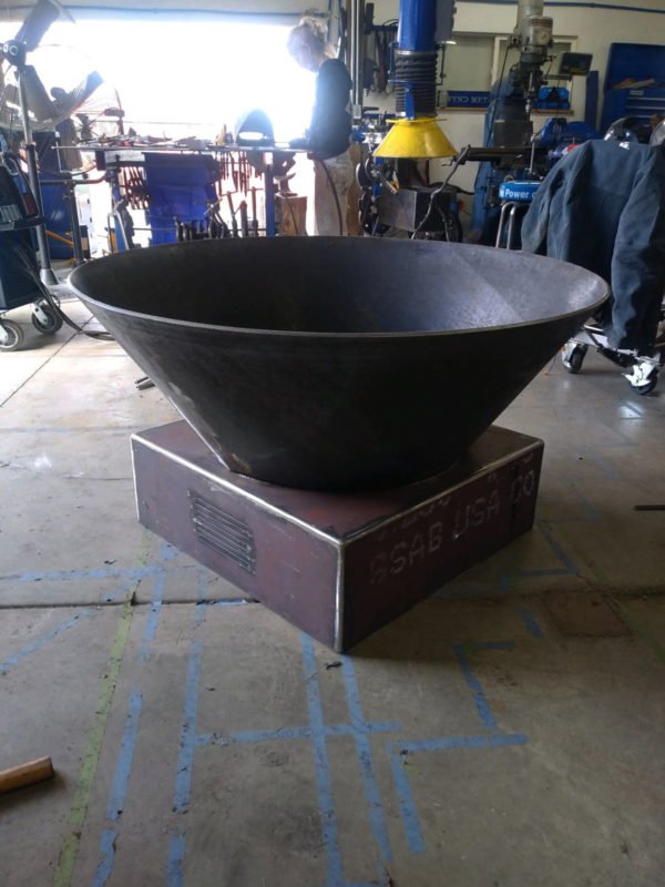 Large steel fire pit created in a cone shape round out at the top